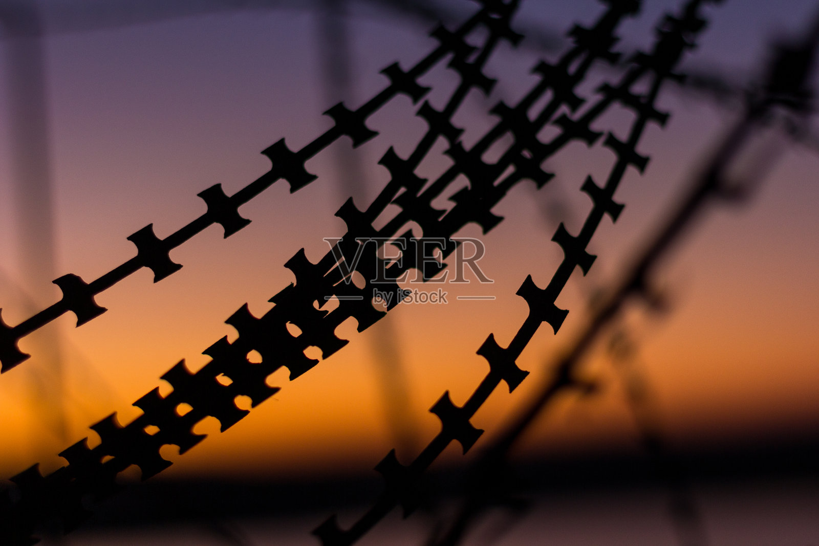 剪影剃刀，带刺的胶带，电线，在晚上的光。照片摄影图片