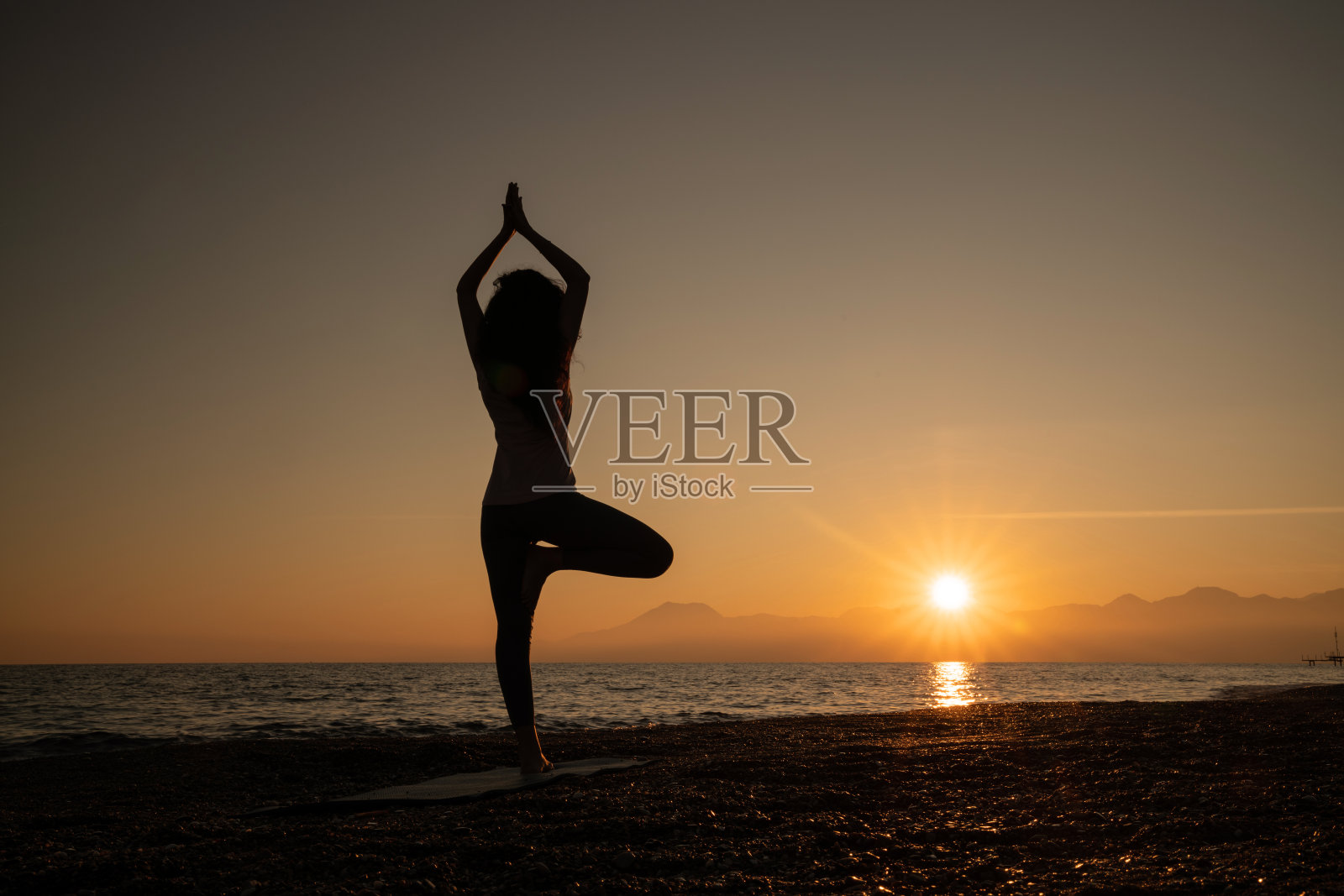 成年妇女在日落时在海滩上沉思的全长照片照片摄影图片