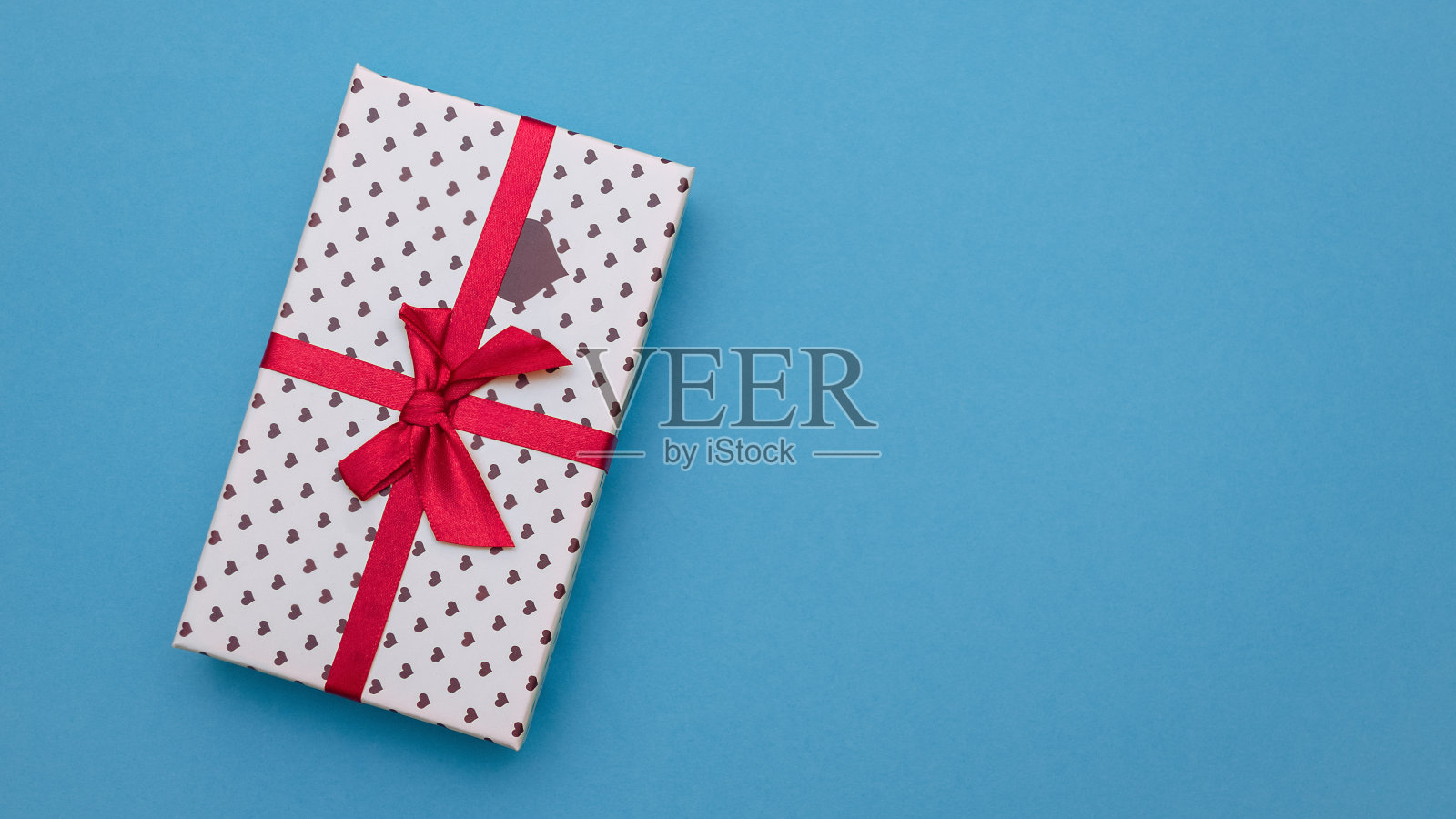 蓝底红丝带的礼物。照片摄影图片