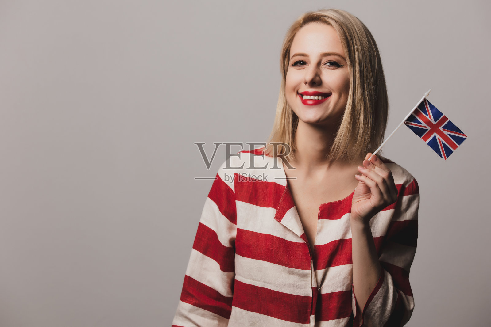 女孩在灰色背景上举着英国国旗照片摄影图片