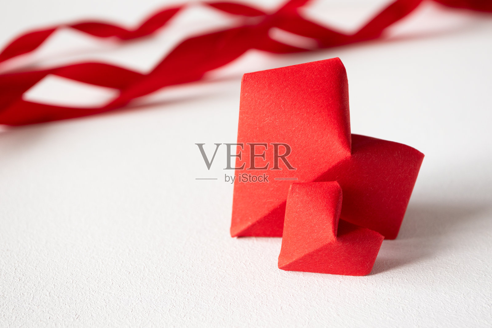 白色背景上的两个红色折纸心和缎带，具有复制空间。情人节或婚礼邀请函、海报、明信片模板。美丽的爱情概念照片摄影图片