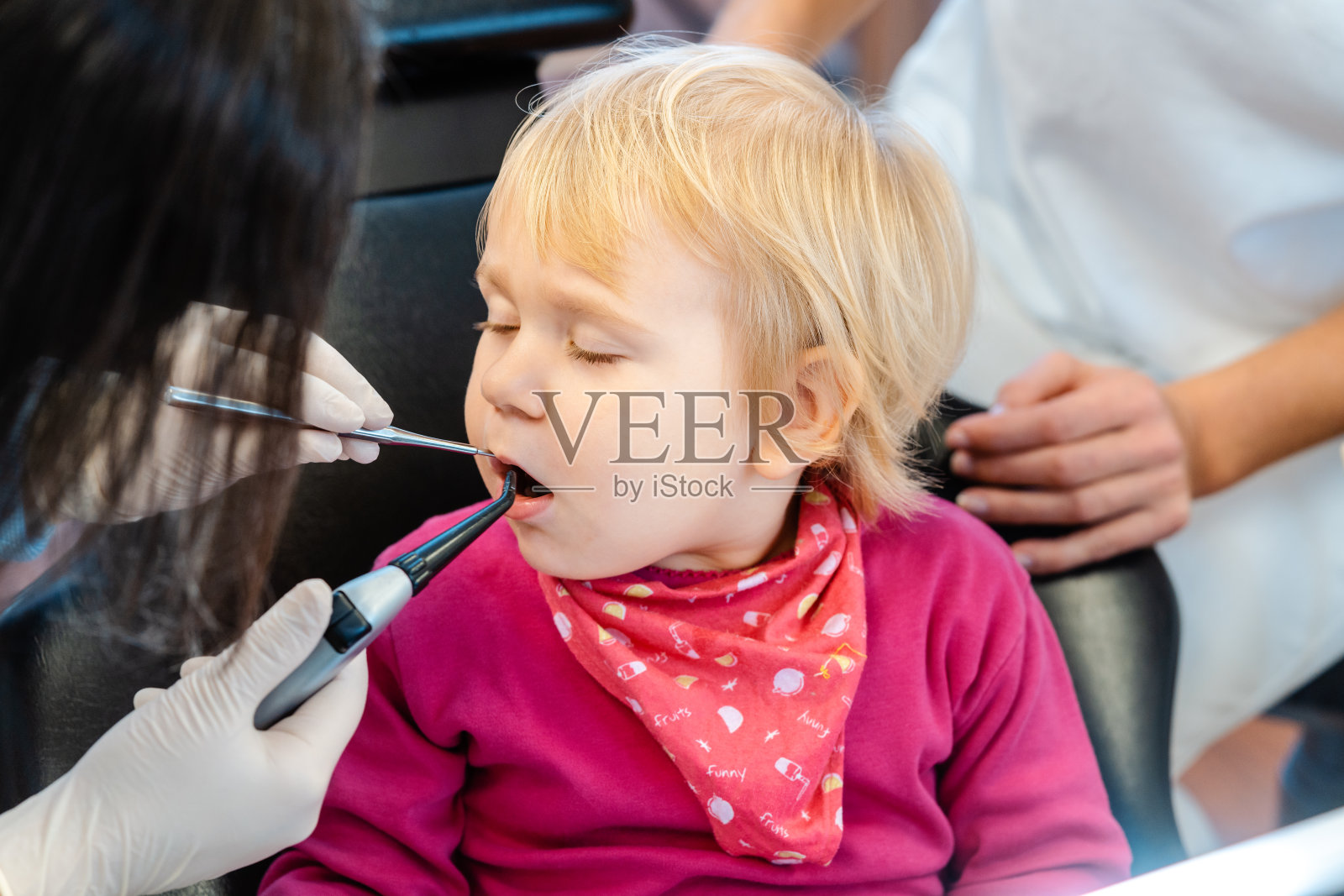 女牙医护理小女孩的乳牙照片摄影图片