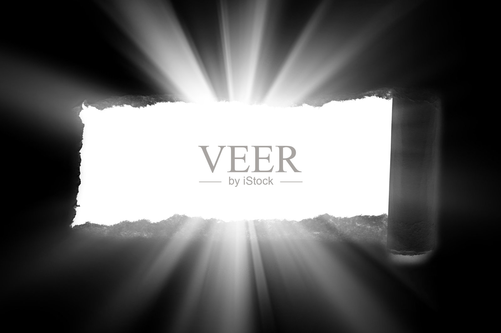 黑纸上一个边缘撕裂的洞，穿透阳光和光线。阳光从一个洞里穿过黑暗。照片摄影图片