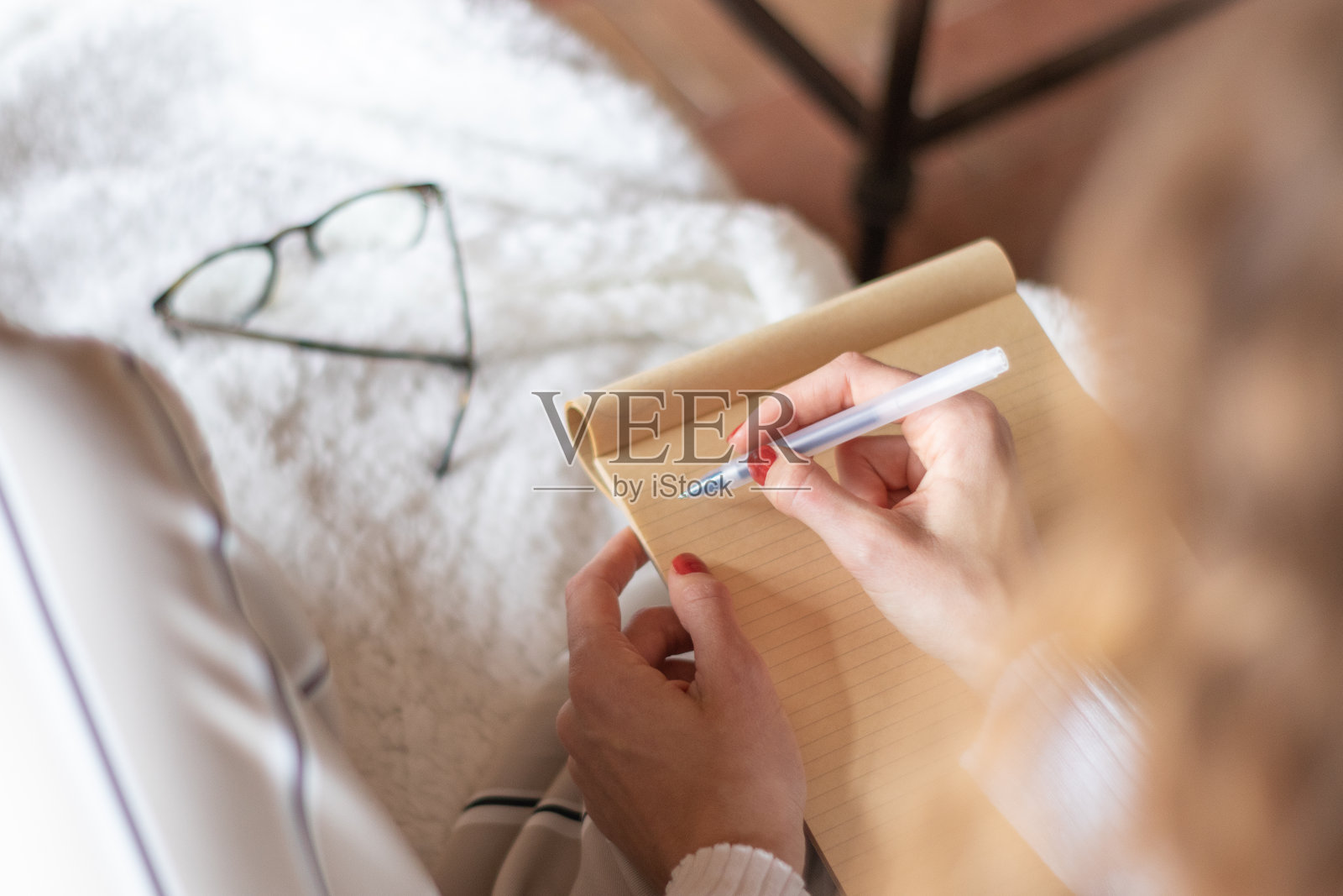 年轻女子开始在家里沙发上的笔记本上写字。照片摄影图片