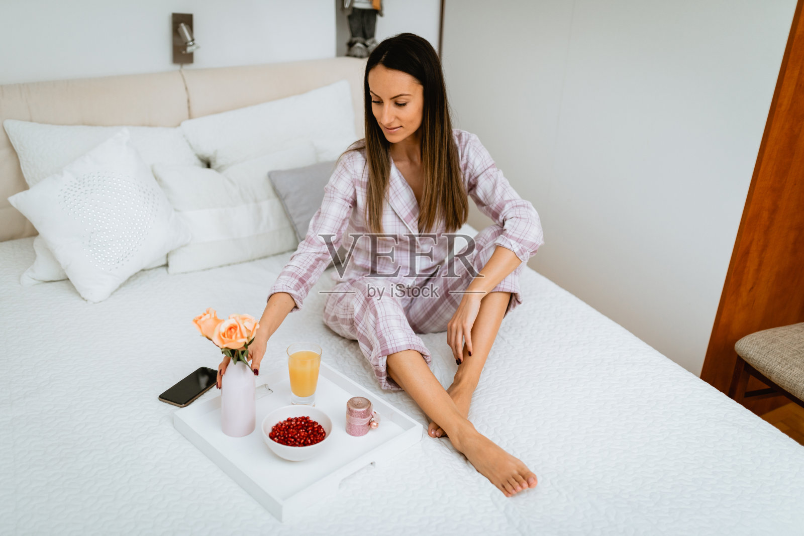 穿着睡衣在床上吃健康早餐的年轻女人照片摄影图片