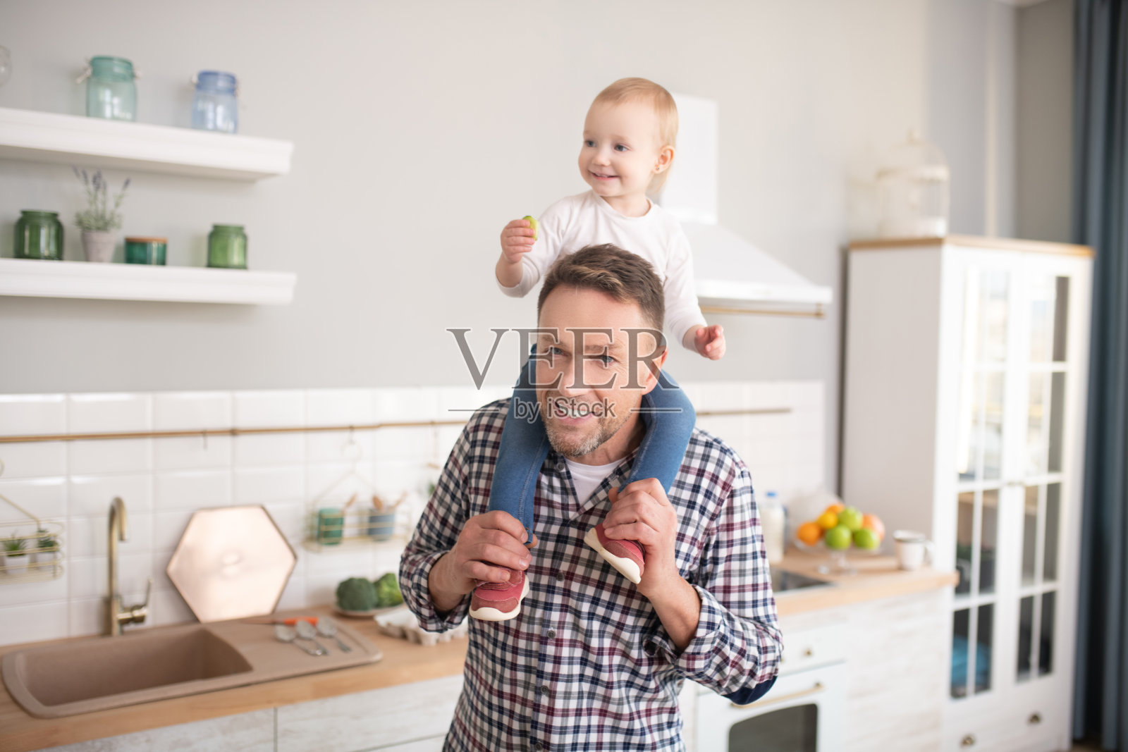 父亲穿着格子衬衫，把小女儿扛在肩上照片摄影图片