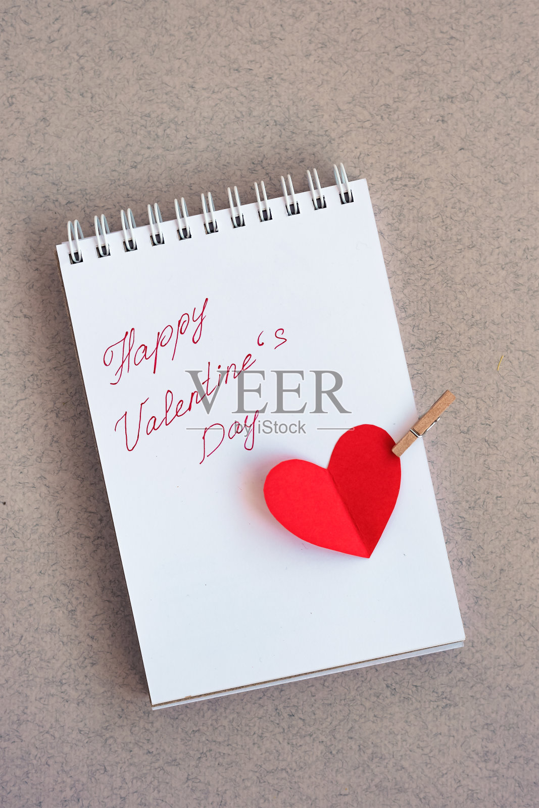 手写文字的笔记本:情人节快乐和用红纸剪出的一颗心照片摄影图片