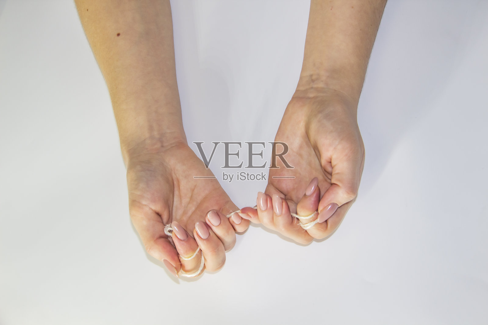 在灯光背景下，女人的手握着绳子。女人的手互相拉着绳子。用手拉绳子。照片摄影图片