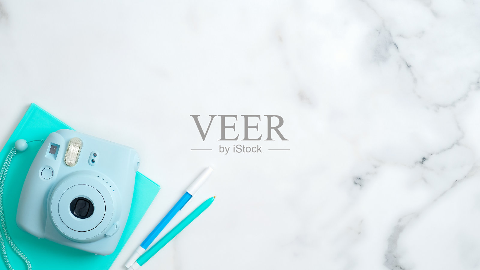 平铺现代即时照相机，薄荷纸笔记本，文具在大理石桌子与复印空间。女孩家庭办公桌，女性工作空间的概念。照片摄影图片