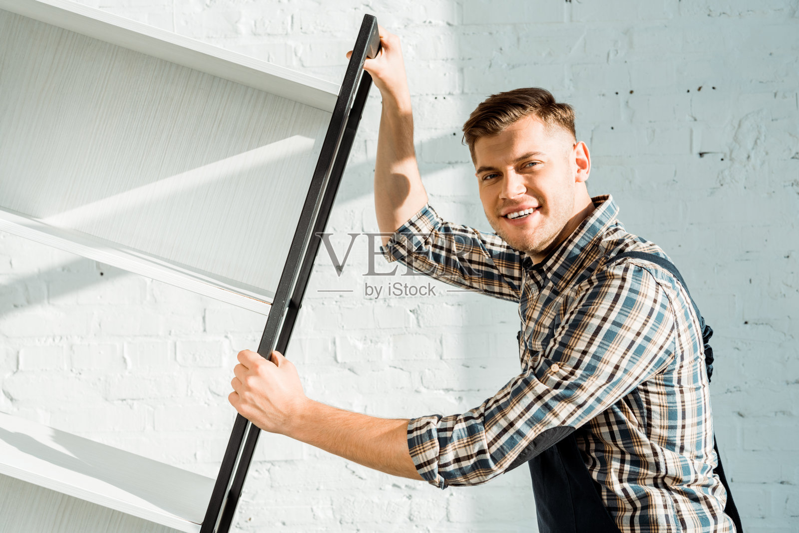 安装人员手持支架靠近砖墙照片摄影图片