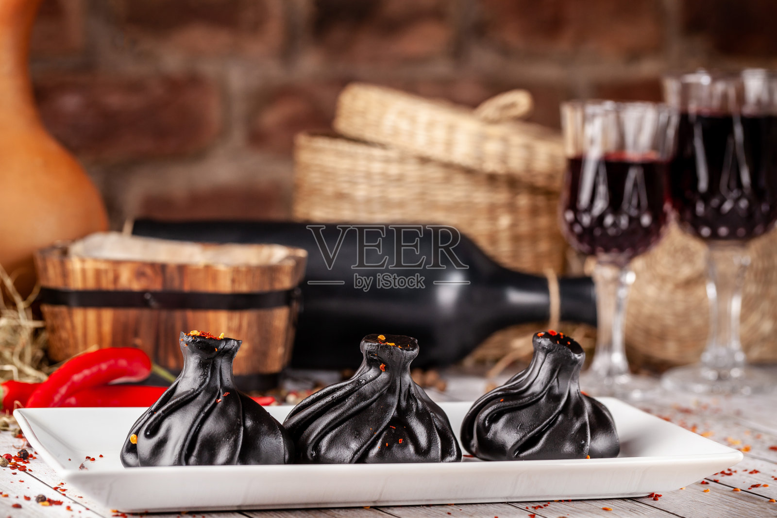 传统的格鲁吉亚和亚美尼亚美食。Trend，格鲁吉亚黑色khinkali，肉和苏鲁古尼奶酪，放在餐厅的一张木桌上。桌上有酒。复制空间，选择焦点照片摄影图片