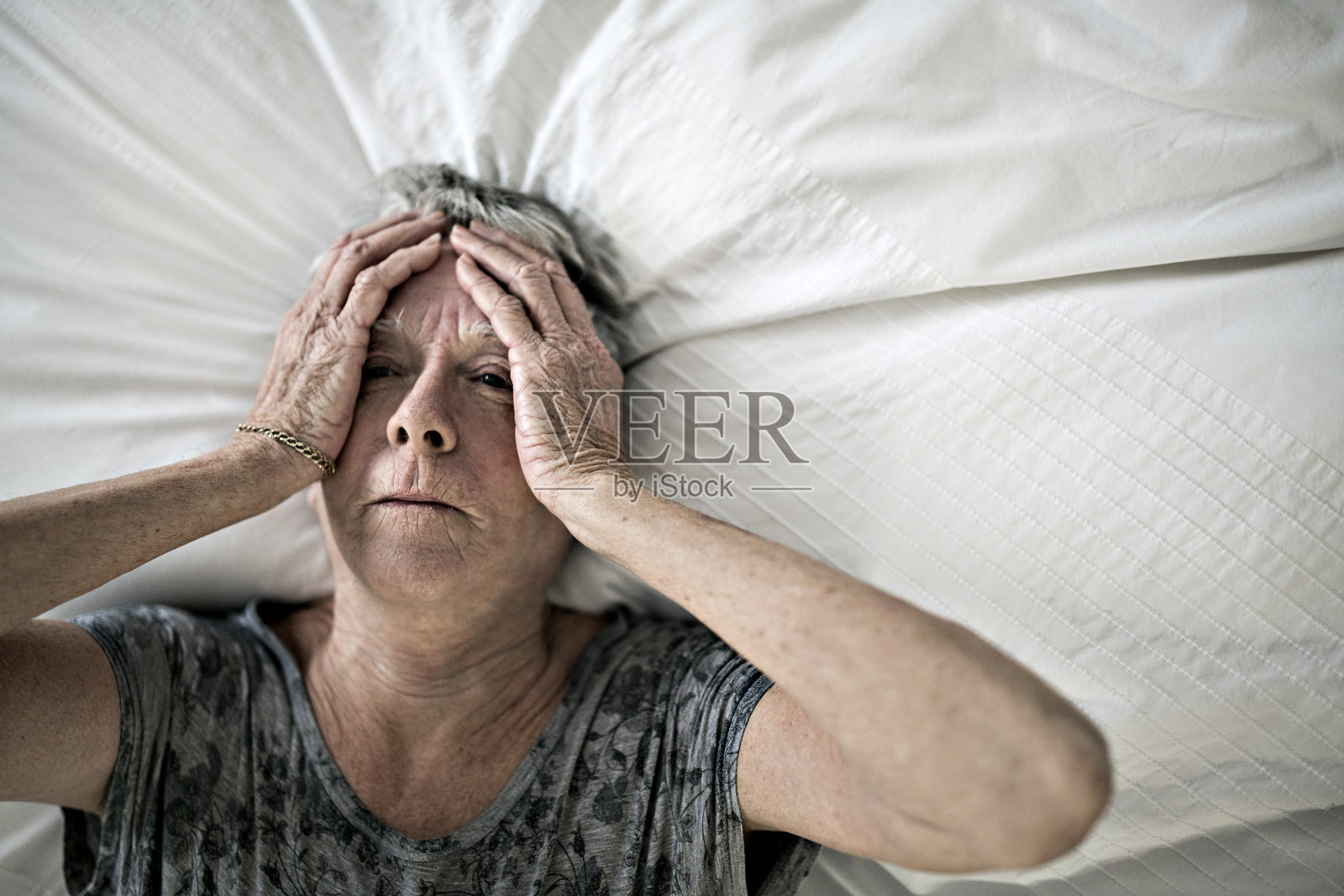 老年妇女躺在家里的床上感到悲伤照片摄影图片