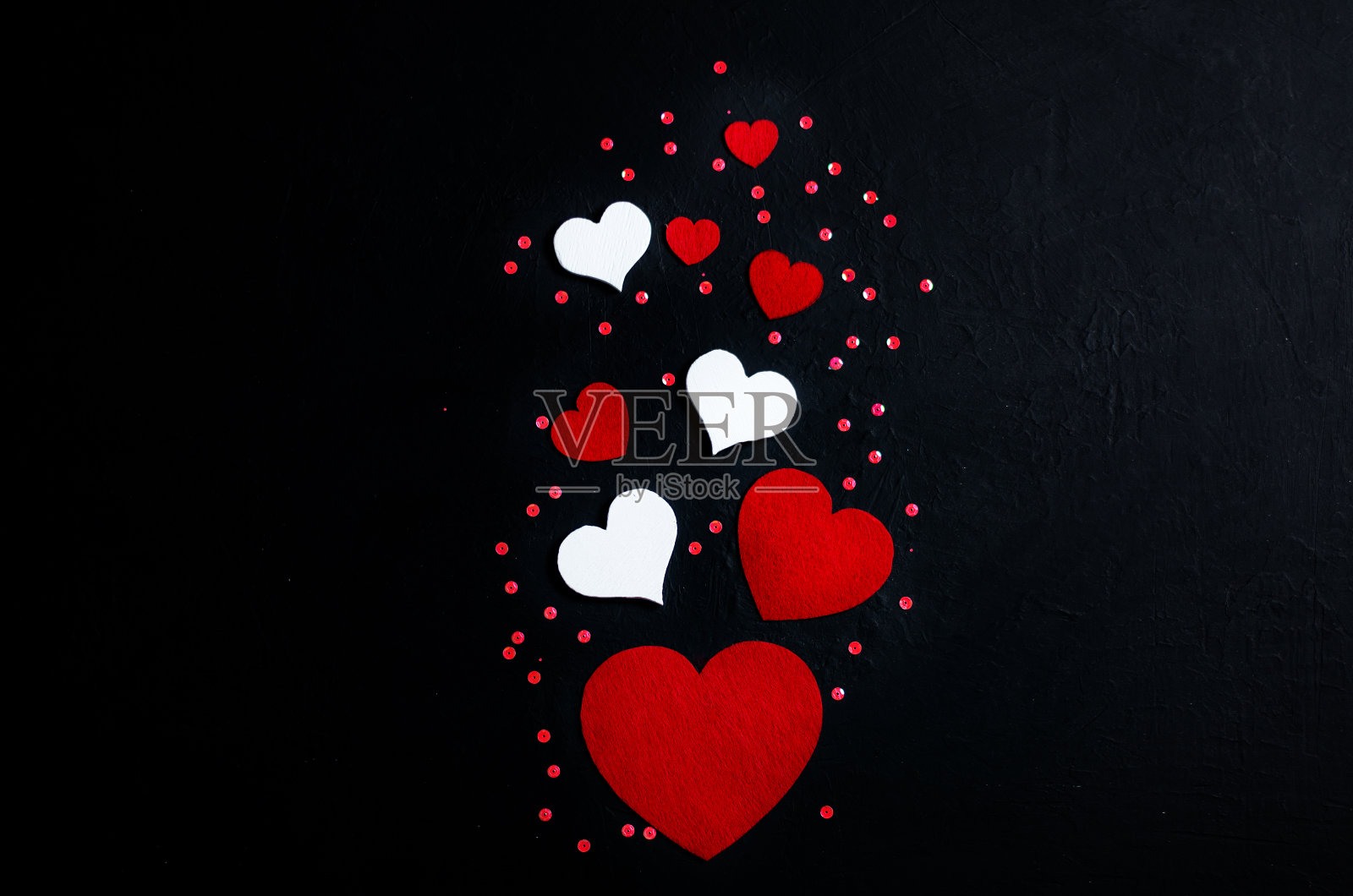 九个不同大小的装饰心，黑色背景上的竖版布局，情人节概念，留白照片摄影图片