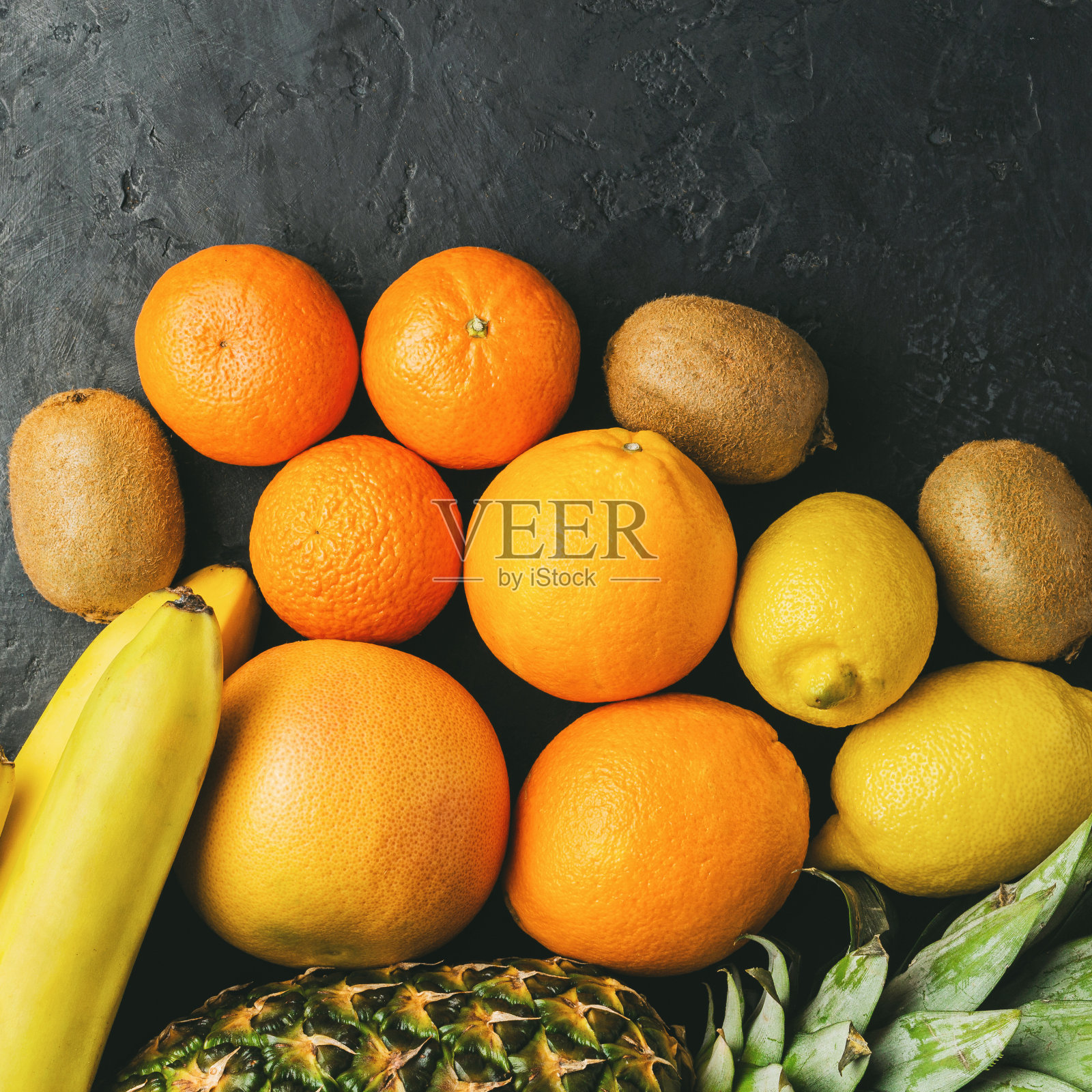 各种热带水果，香蕉，猕猴桃，橙子，橘子，柠檬，菠萝，葡萄柚在黑暗的背景，俯视图，拷贝空间照片摄影图片