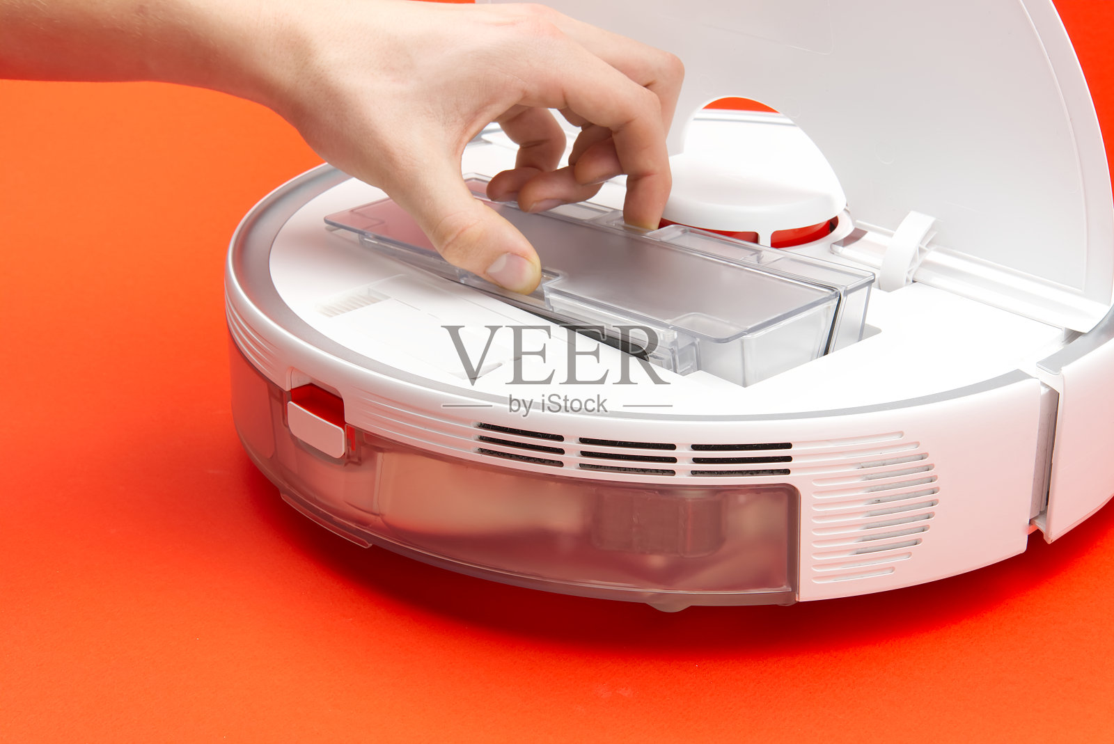 清洁垃圾箱和过滤器的扫地机器人，红色背景照片摄影图片