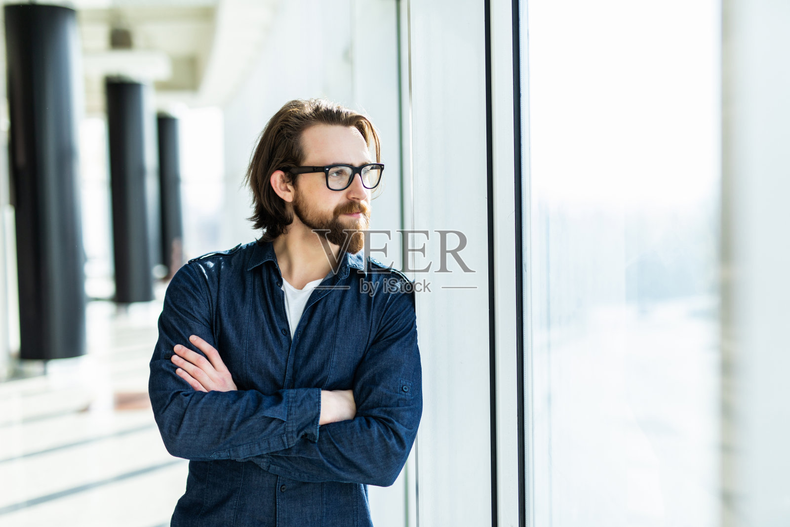 戴眼镜的英俊自信员工站在办公室的桌子旁，双手交叉微笑照片摄影图片