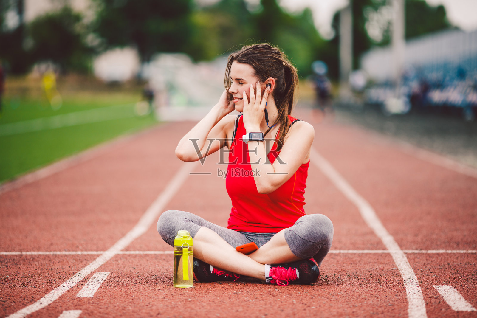 健康生活方式、运动音乐主题。年轻的白人女性在跑步机上休息，使用手机并将耳机插入耳朵，包括音乐训练照片摄影图片