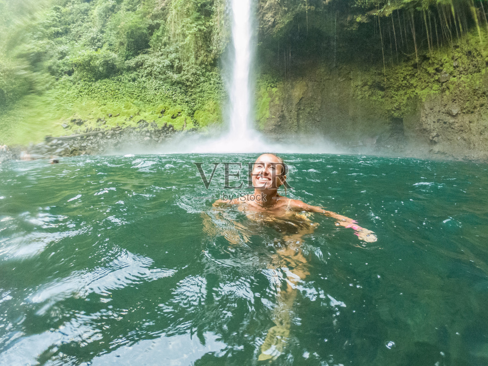 年轻女子在哥斯达黎加的瀑布中游泳照片摄影图片