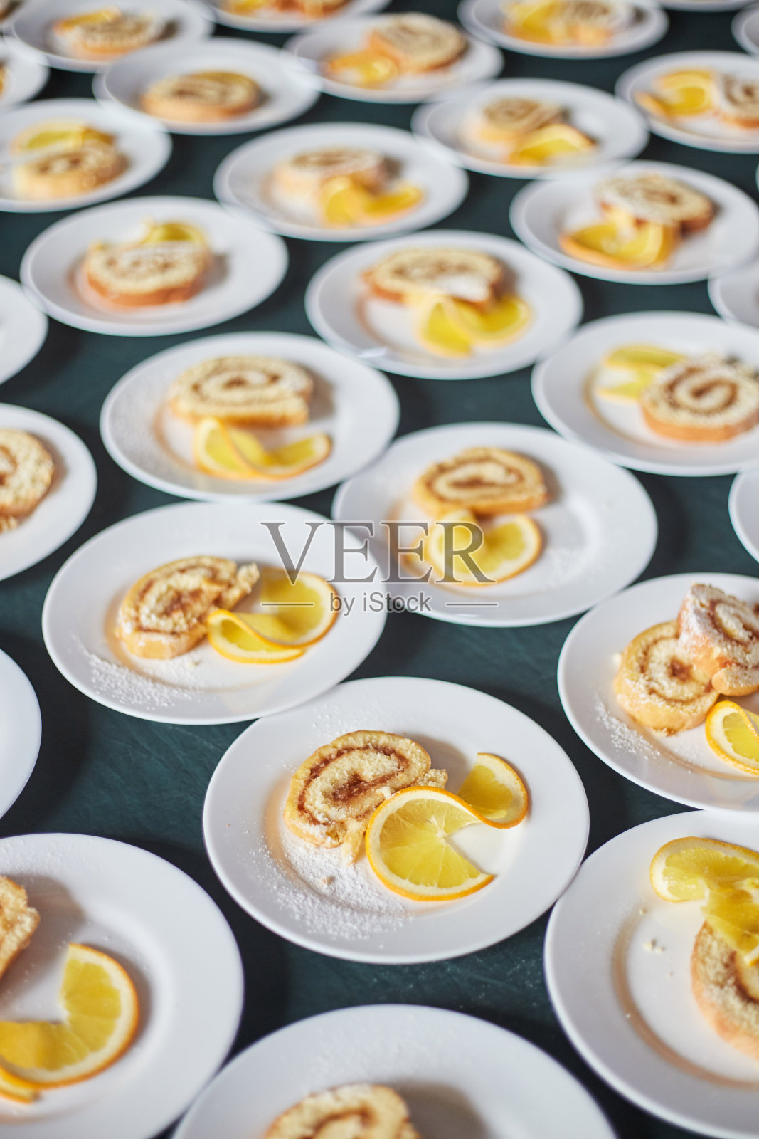 白色的盘子上放着海绵卷、果酱和一片橙子。背景照片摄影图片