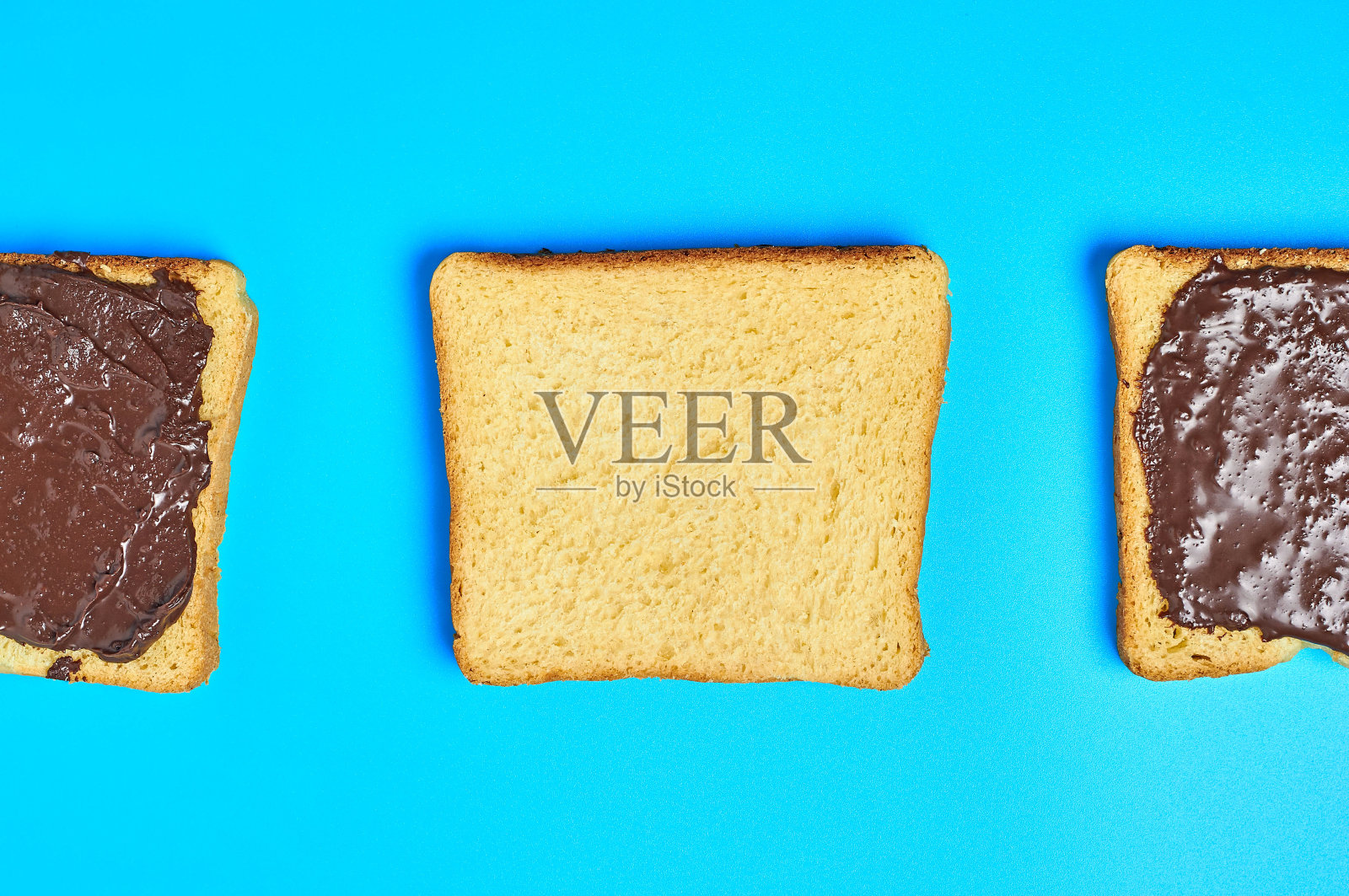 厨房蓝色的桌子上放着一排方形的香草面包，上面放着融化的巧克力或奶油。营养早餐或午餐的概念。俯视图照片摄影图片