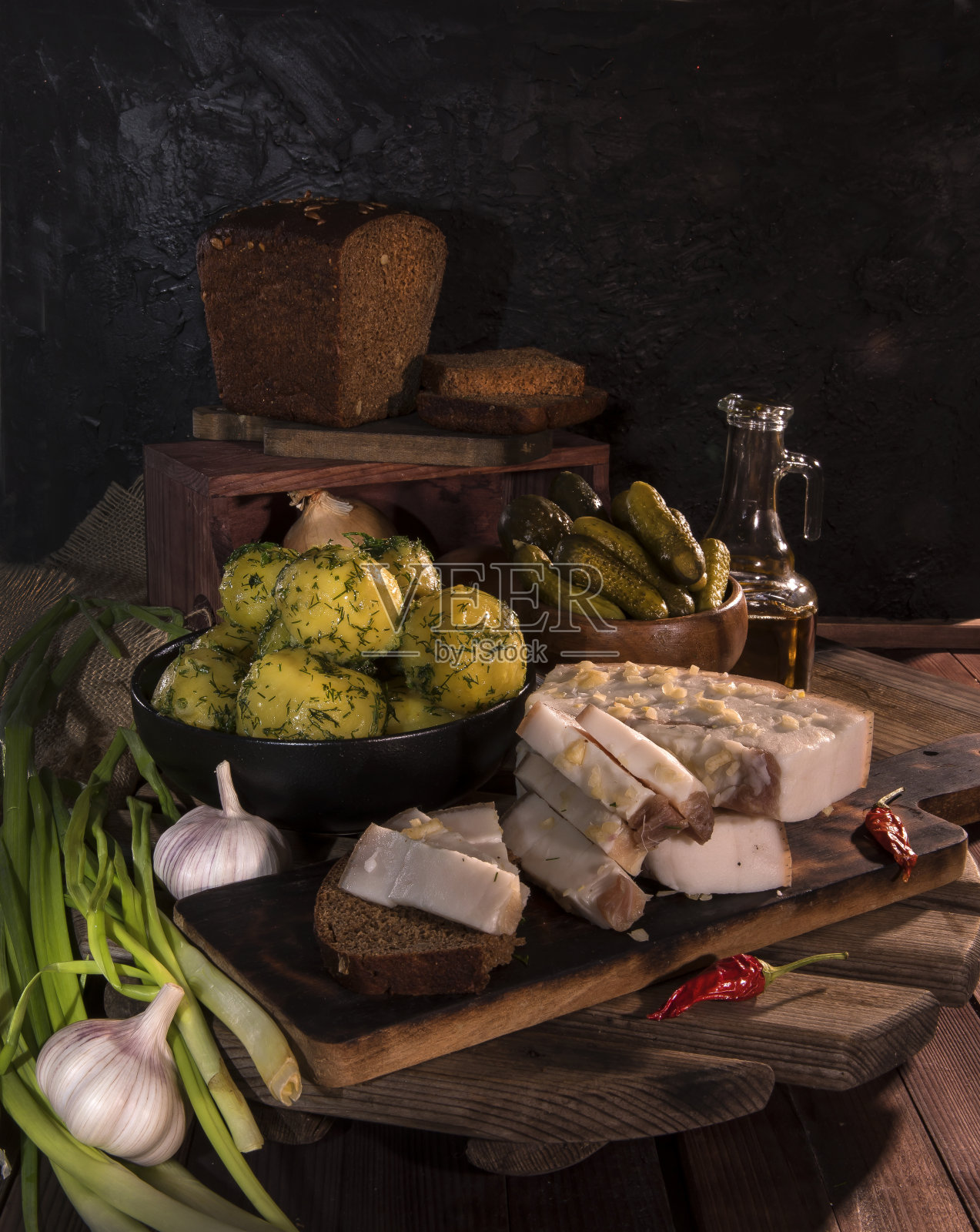 木背景上放着猪油、煮土豆、面包、黄瓜和大葱。俄罗斯和乌克兰传统的开胃菜，黑面包和猪油。一种美味的培根小吃照片摄影图片