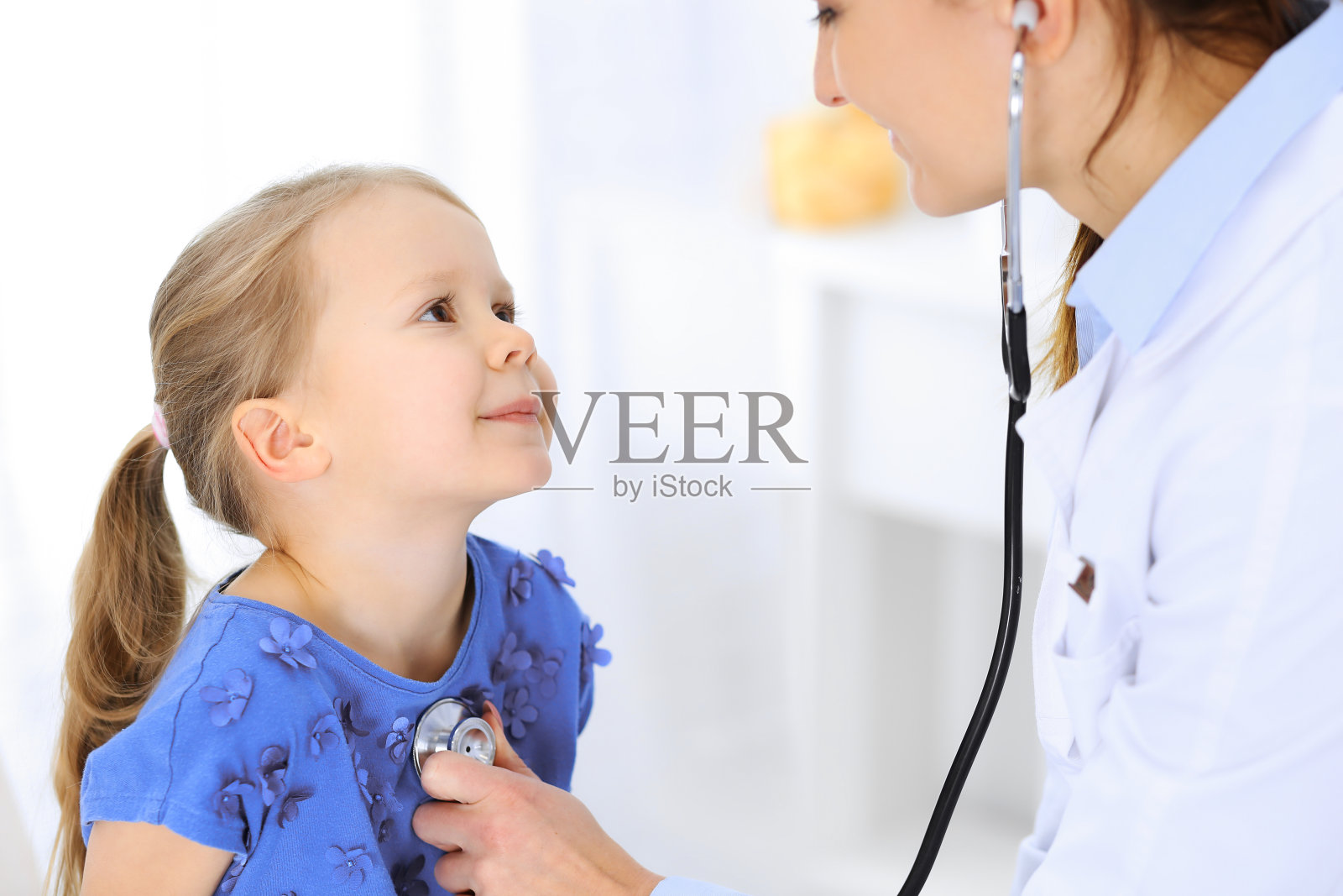 医生正在用听诊器检查一个小女孩。开心微笑的孩子病人在平时的医疗检查。医学和保健概念照片摄影图片