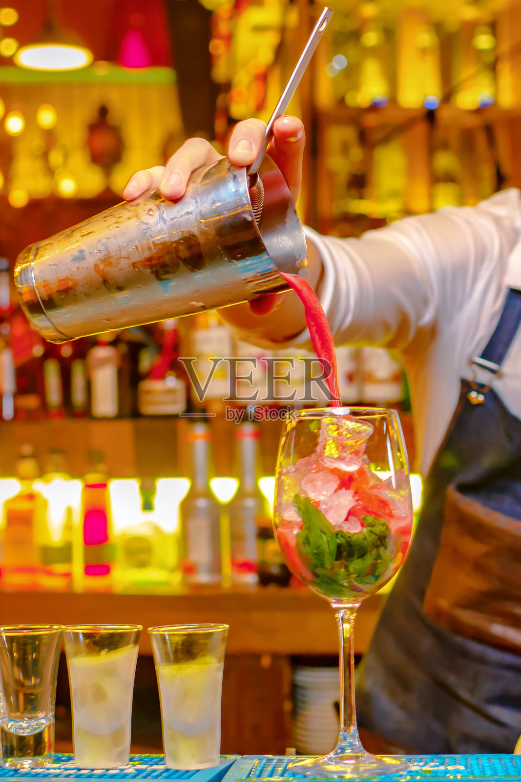 酒保在酒瓶背景下调制鸡尾酒照片摄影图片