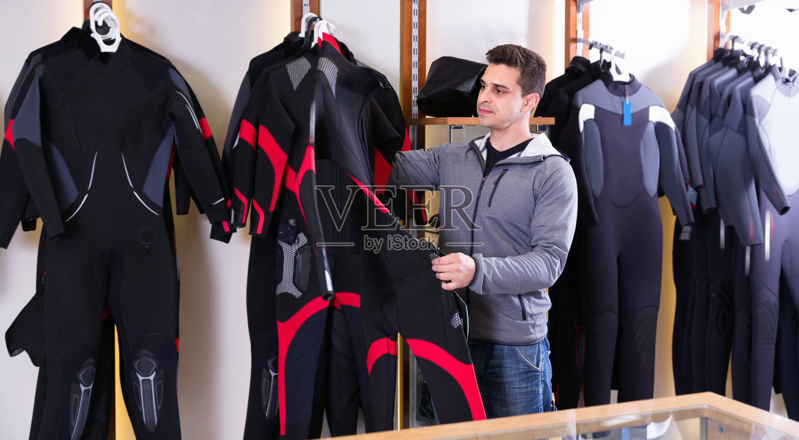 男子站在商店里，穿着现代潜水服。照片摄影图片