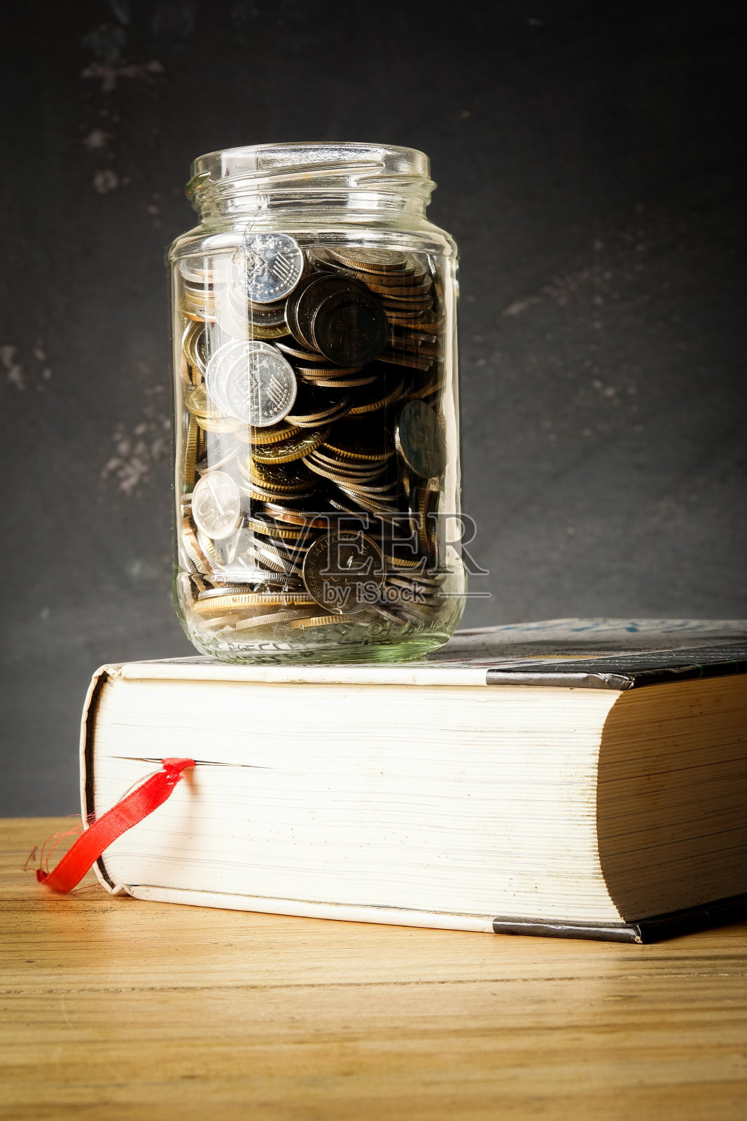 教育基金概念与硬币在一个玻璃罐和旧书。照片摄影图片