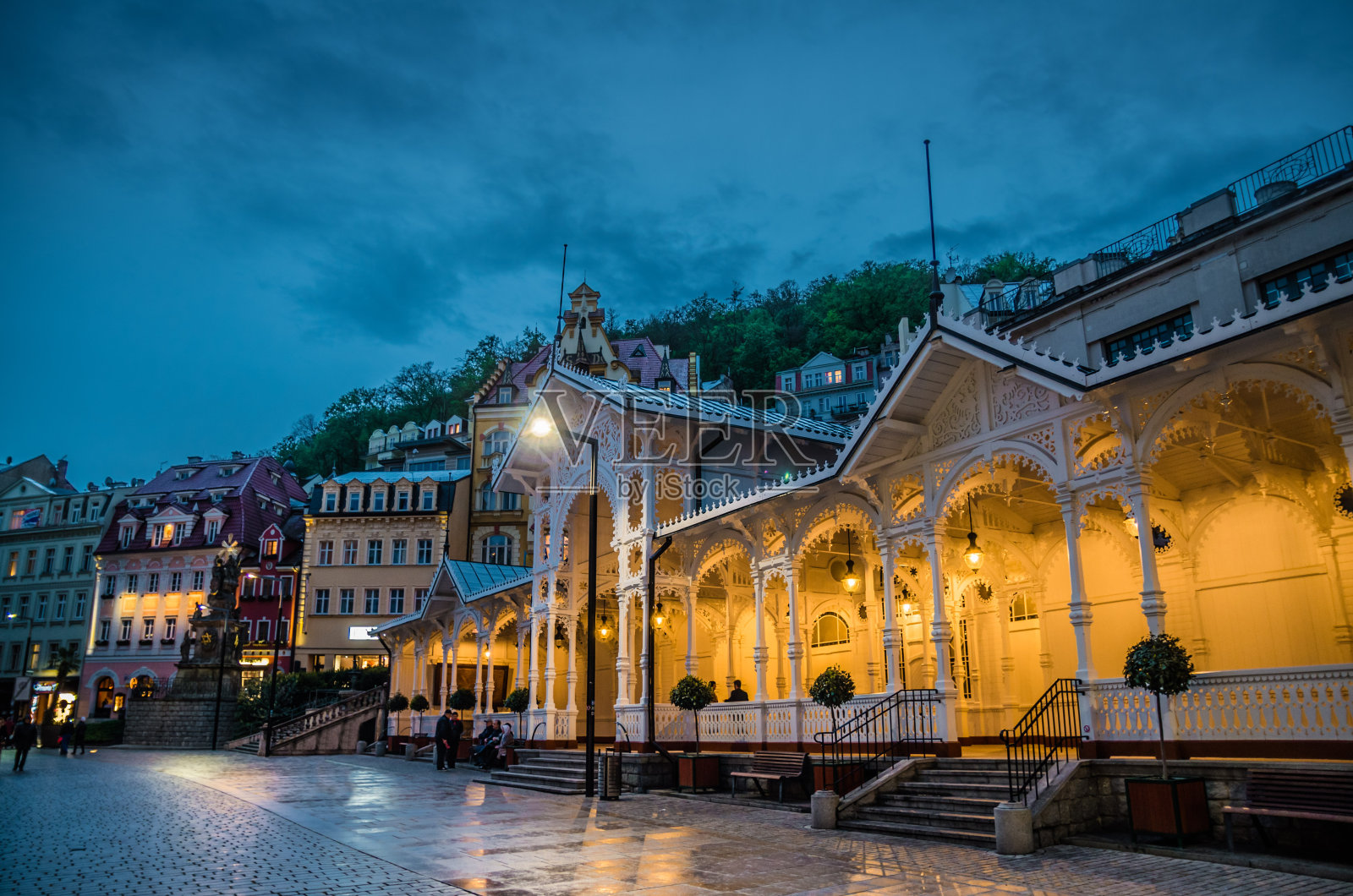 捷克西波西米亚的卡尔罗维法利卡尔斯巴德历史市中心的Trzni kolonada木制柱廊，带有灯光和温泉，夜景照片摄影图片