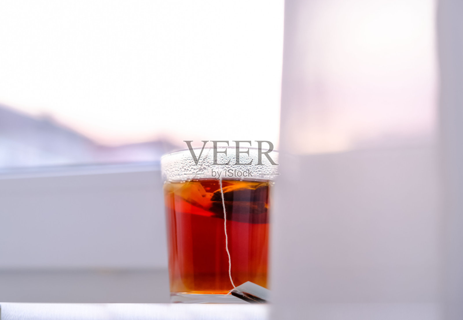 透明玻璃杯中的红茶：白色窗台上的早餐照片摄影图片