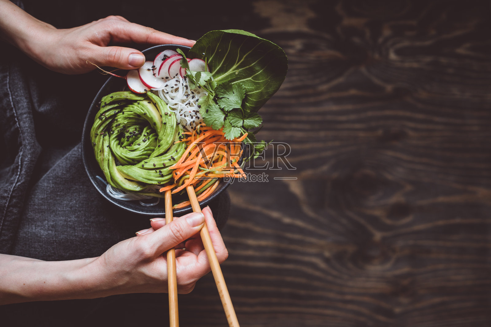 吃生的素食碗，米线，蔬菜和鳄梨在木制的背景照片摄影图片