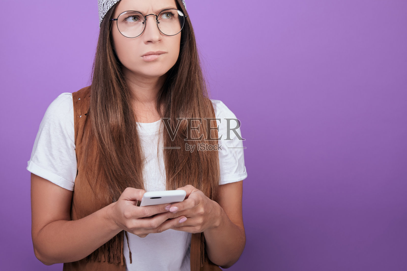 戴圆眼镜的女孩拿着手机，把目光移开。照片摄影图片