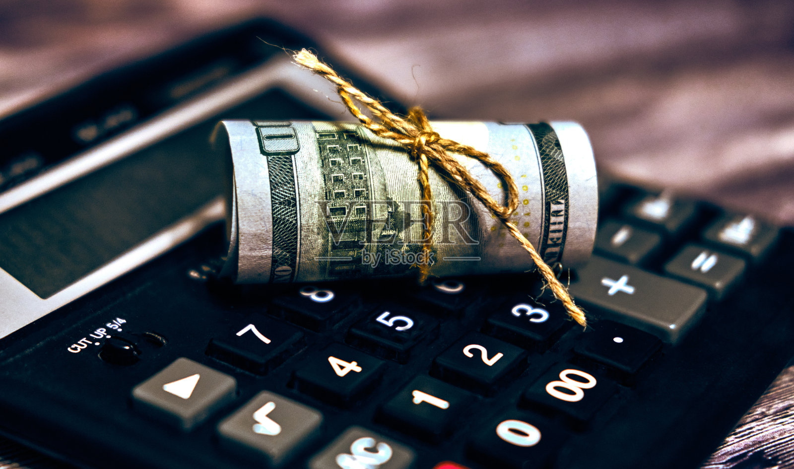 钱在计算器上的管子里卷了起来照片摄影图片