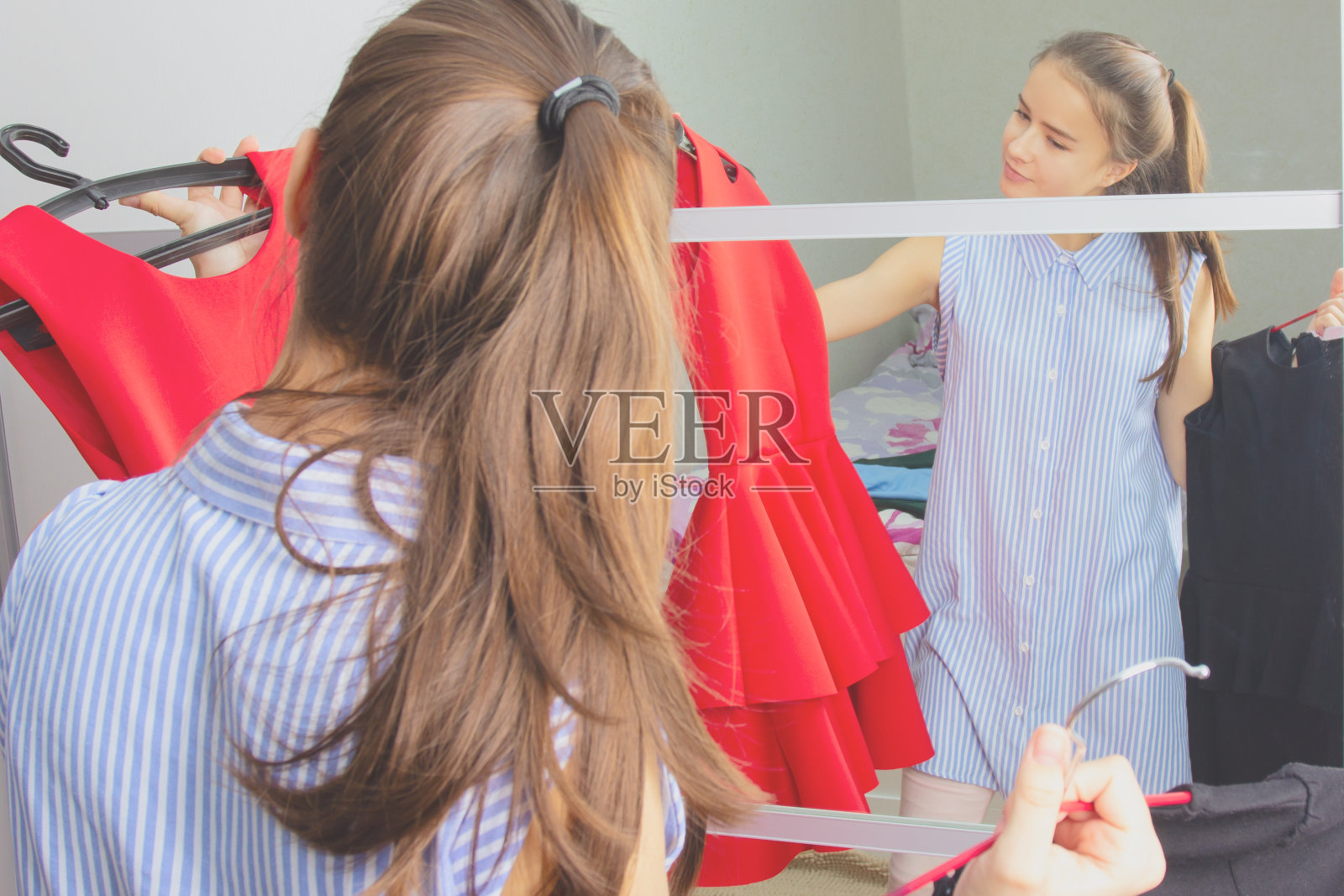 在家中镜子前试穿衣服、选择服装的女孩照片摄影图片