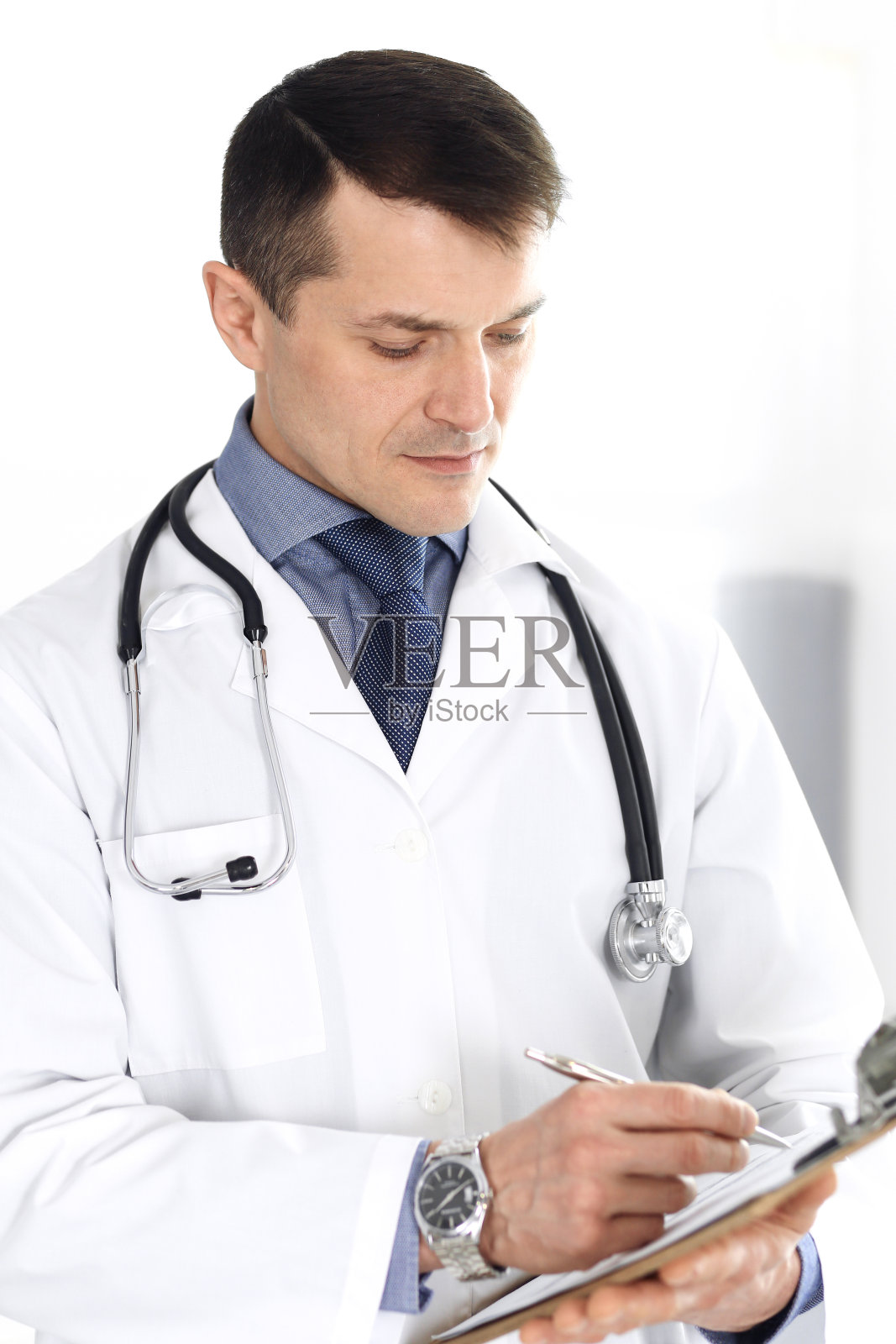 男医生使用剪贴板填写用药史记录。诊所提供完善的医疗服务。医生在医院工作。医学和医疗保健概念照片摄影图片