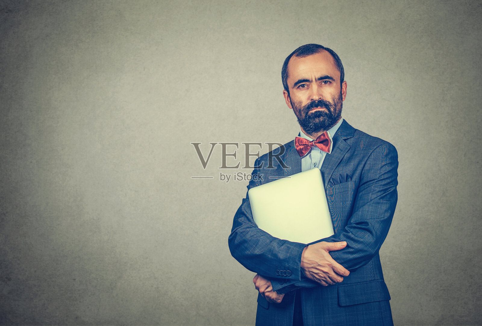 身穿商务服装的男子拿着笔记本电脑，表情严肃照片摄影图片