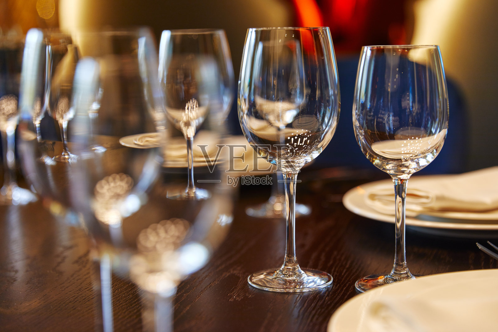 空玻璃杯，高脚杯，玻璃杯放在紧挨着盘子的木桌上照片摄影图片