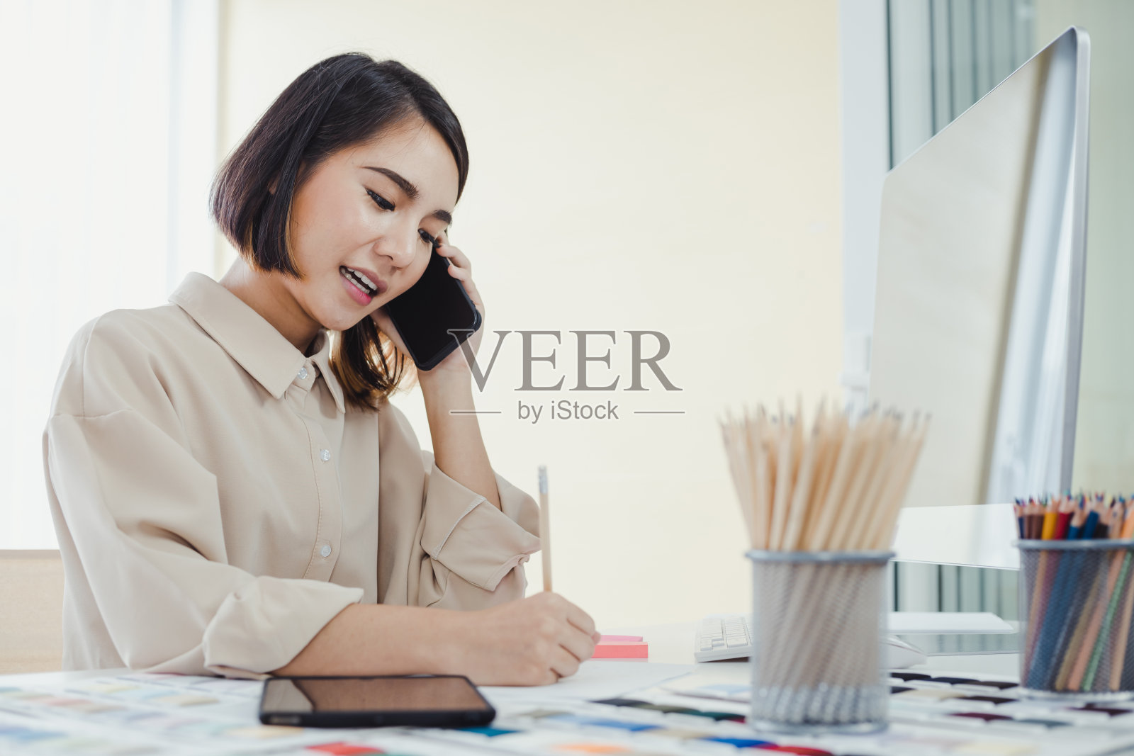 亚洲女设计师与顾客通电话并记录工作细节照片摄影图片