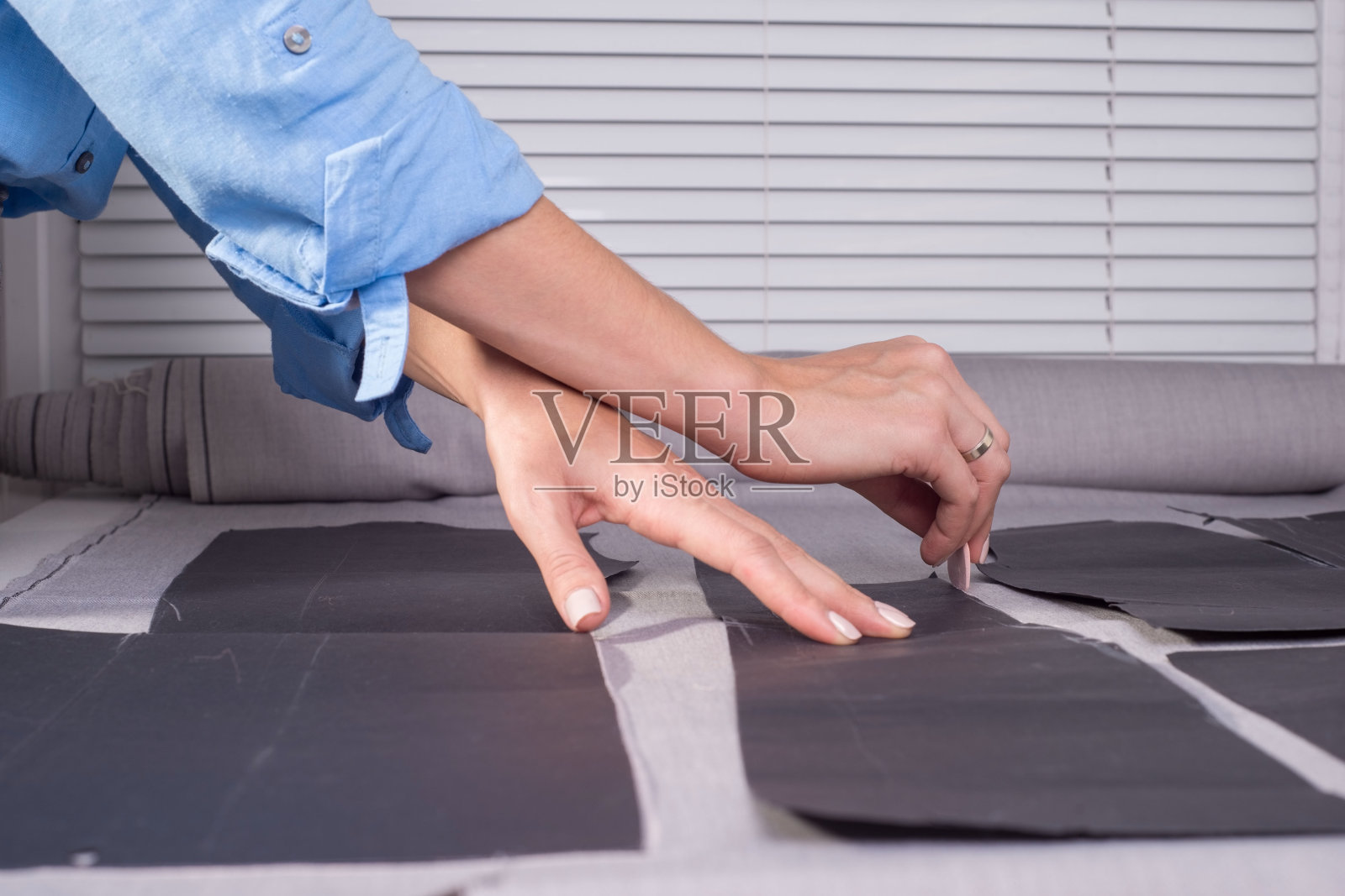 女装设计师在桌旁用尺子和铅笔测量织物上的缝纫边缘照片摄影图片