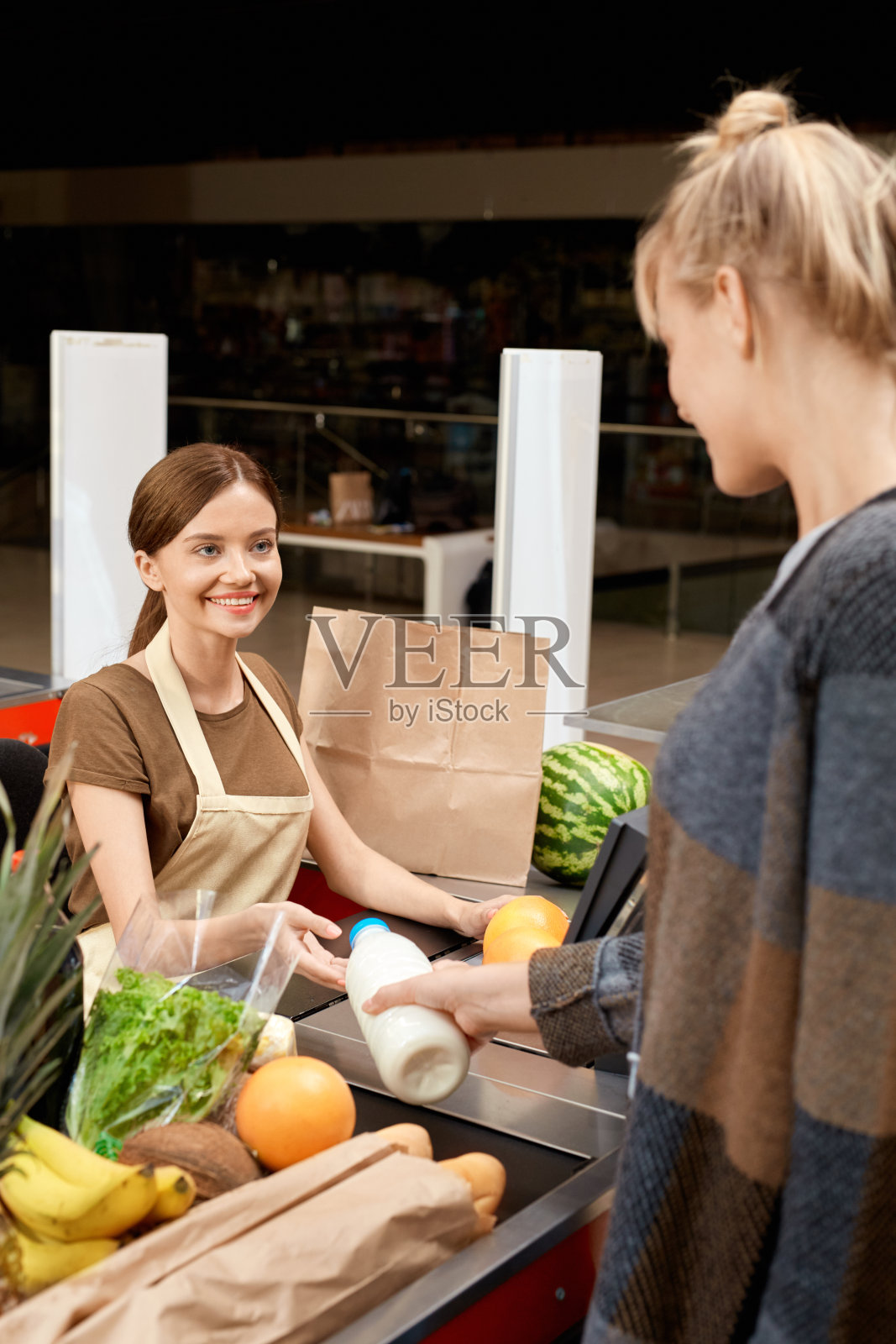日常购物。女人站在收银台给牛奶瓶结账收银员微笑快乐照片摄影图片