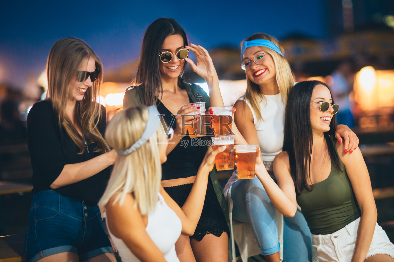 在音乐节上坐着喝啤酒欢呼的女性朋友们照片摄影图片