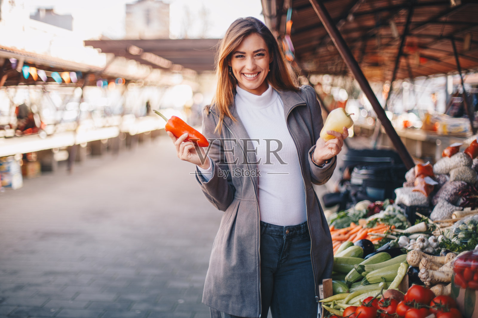 一个妇女在户外农贸市场采摘蔬菜。照片摄影图片