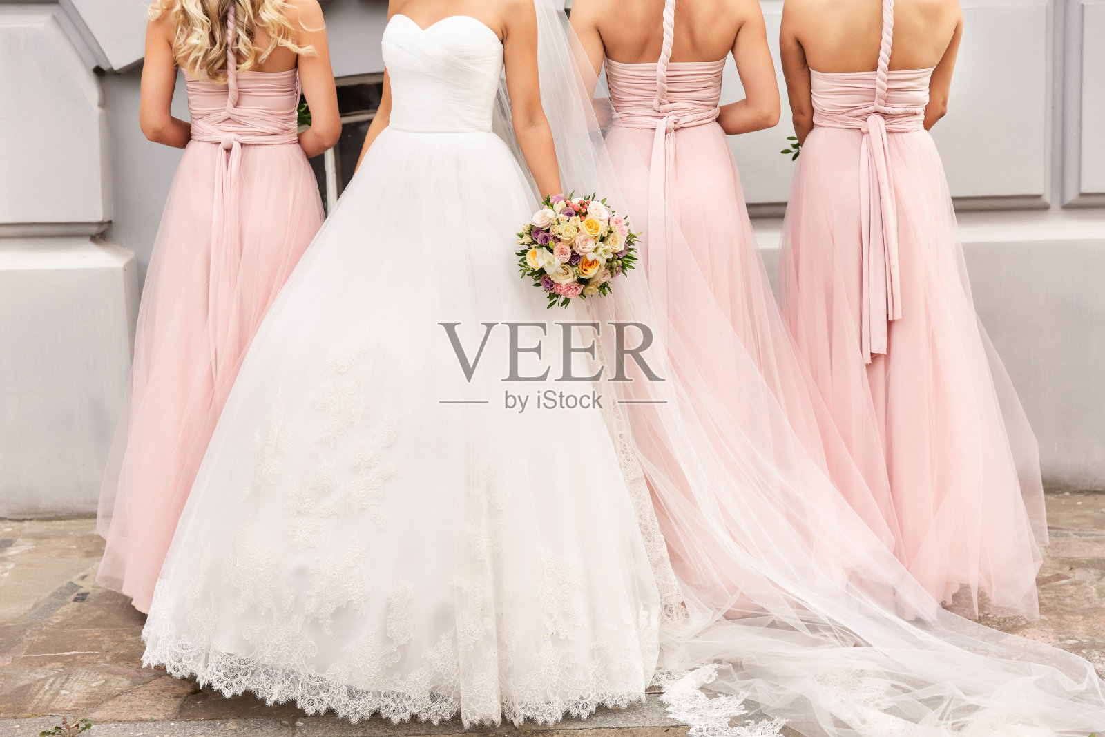 婚礼当天，穿着粉色礼服的新娘和伴娘拿着花束合影，幸福的婚姻和婚礼派对概念照片摄影图片