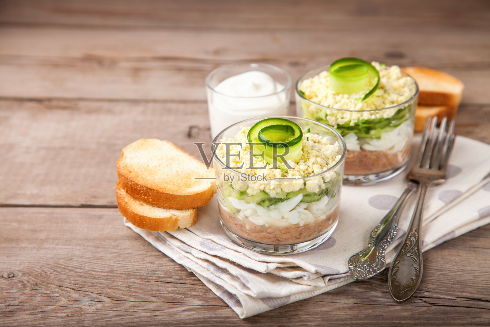 把金枪鱼、黄瓜和鸡蛋沙拉放在桌上的玻璃杯里。有选择性的重点。本空间照片摄影图片