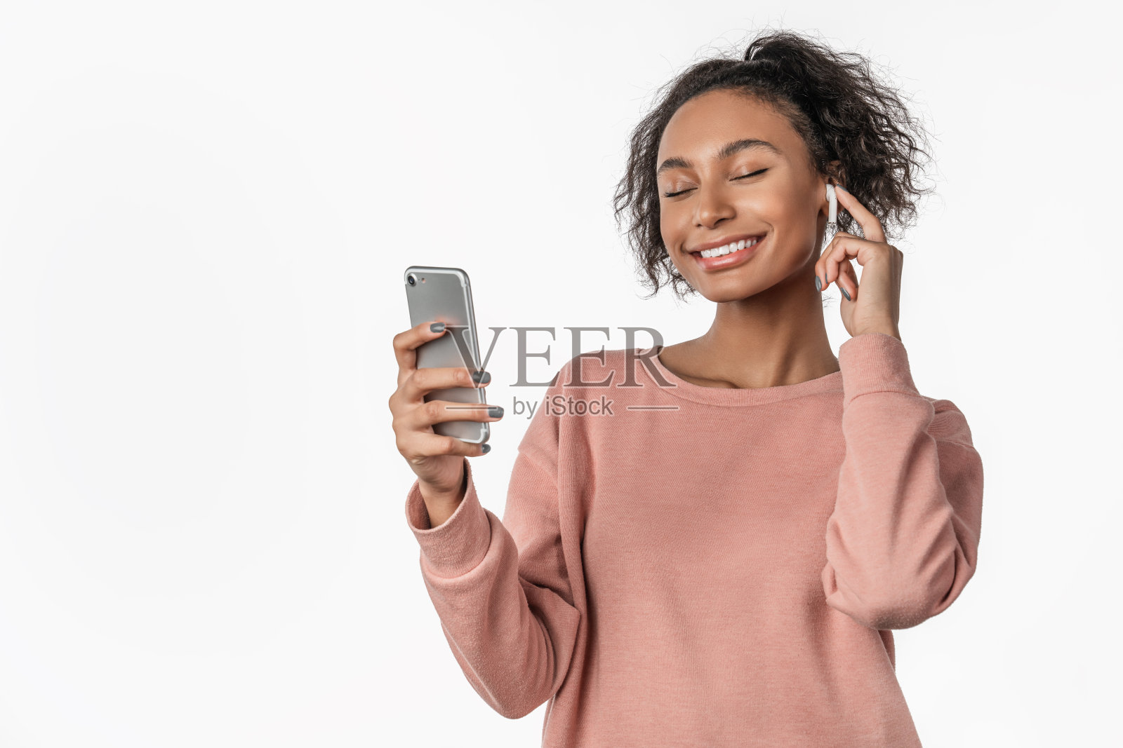 年轻女子戴着耳机欣赏音乐，在白色背景下独自跳舞照片摄影图片