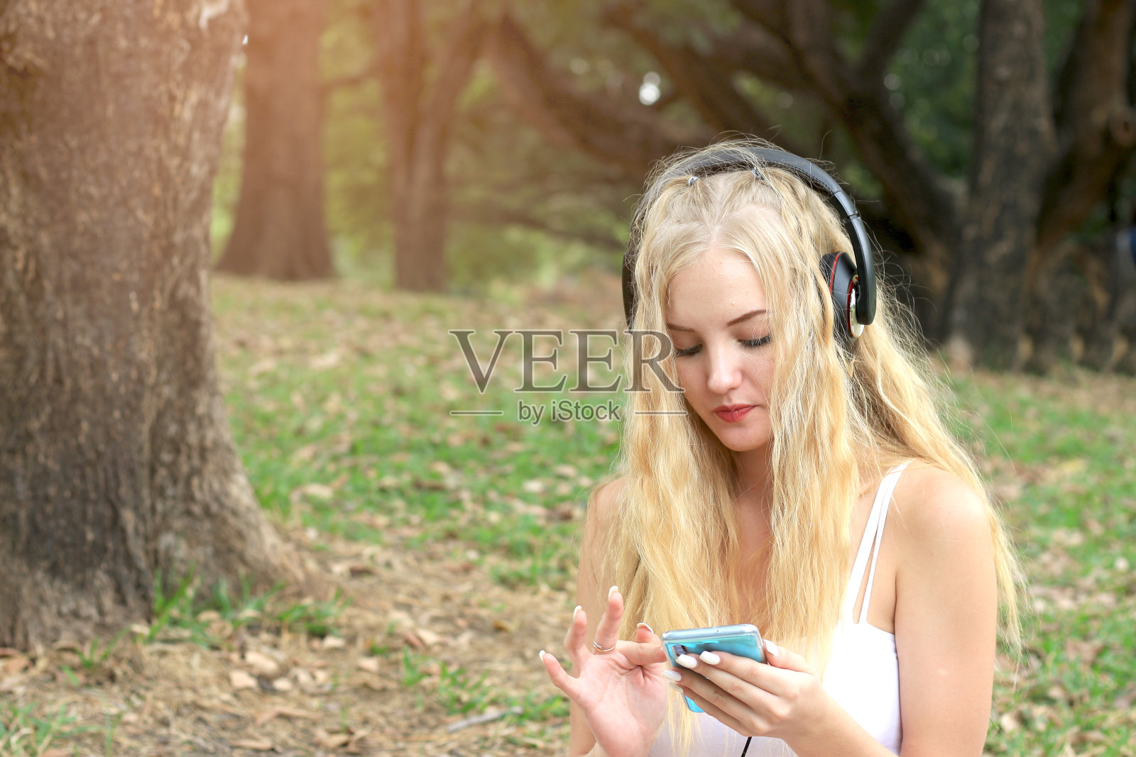 在公园野餐放松的快乐金发女子，年轻漂亮的女孩在花园里听音乐，享受户外休闲时光照片摄影图片