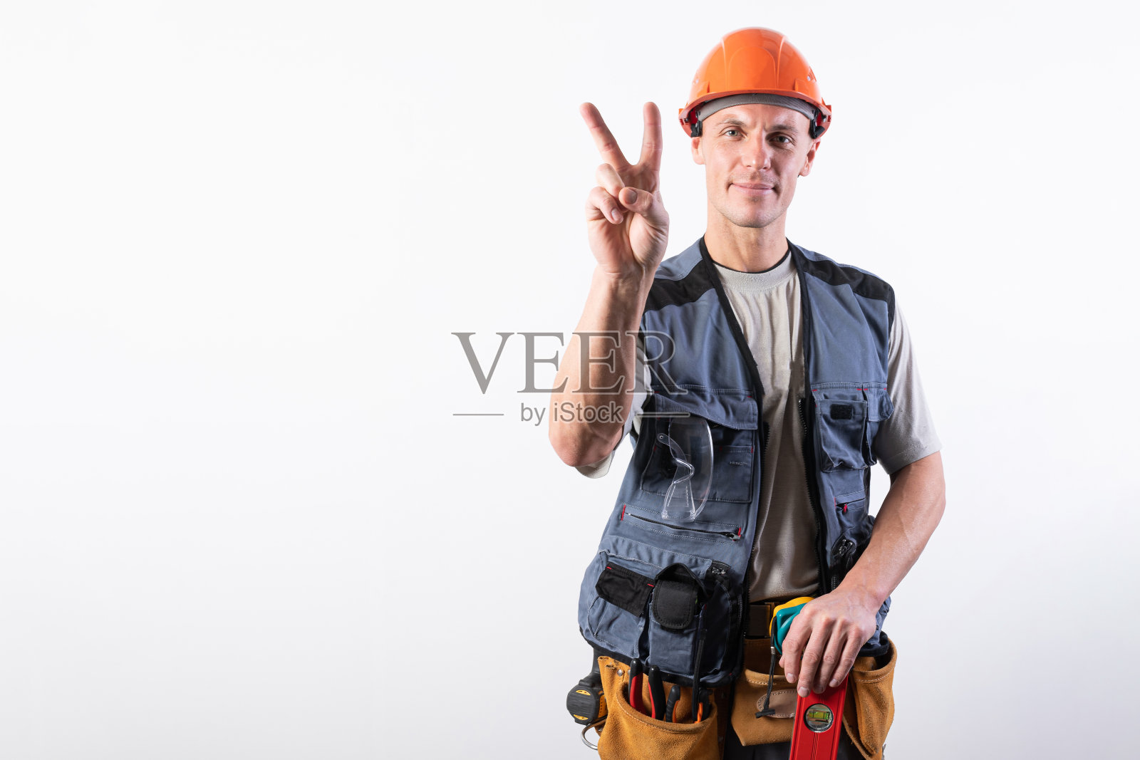 建筑工人展示山羊手势，身穿工作服和头盔照片摄影图片