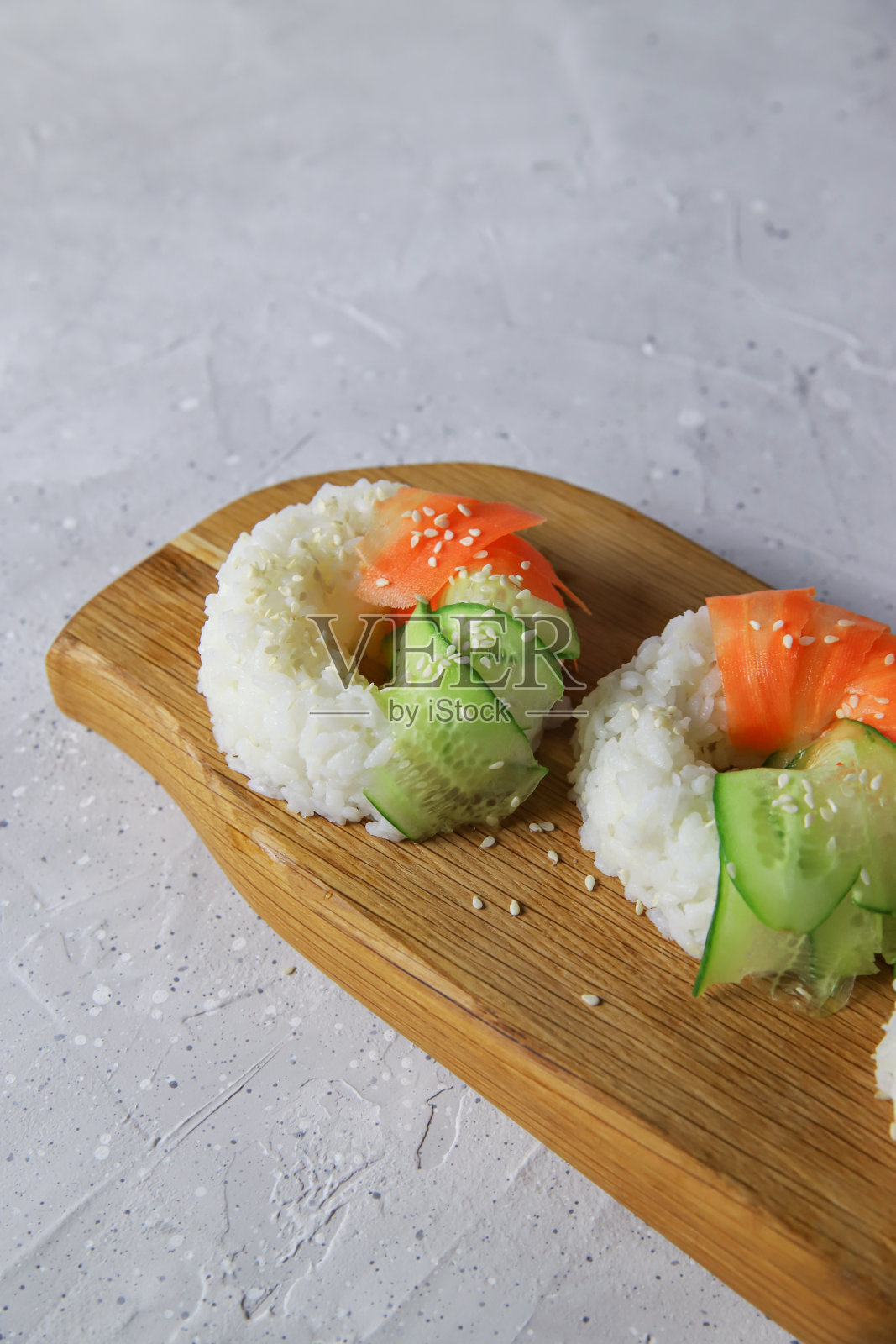 素食寿司甜甜圈配生胡萝卜和黄瓜。木板上的素食百吉饼照片摄影图片