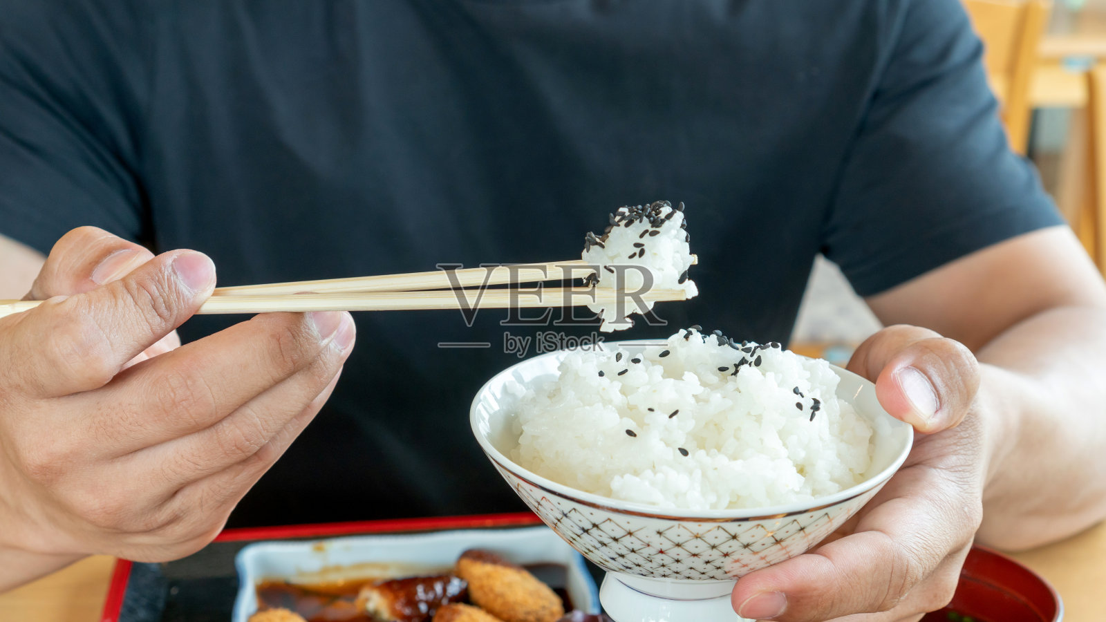 男子手持筷子和一碗日式米饭，背景为日本食物照片摄影图片